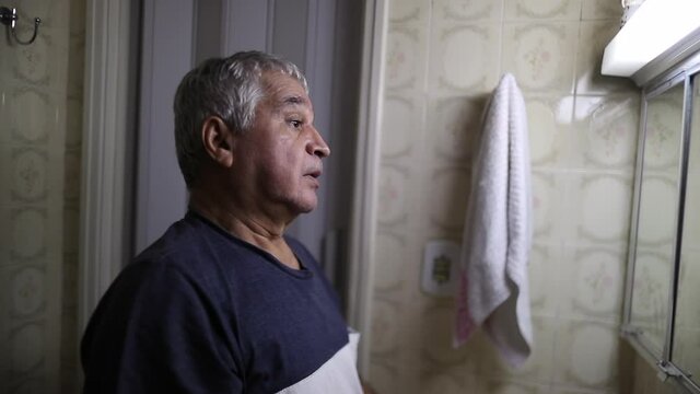Senior man older man in crisis in front of bathroom mirror