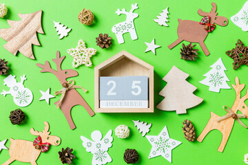 Christmas green background with holiday toys and decorations. Top view of wooden calendar. The twenty fifth of December. Merry Christmas concept