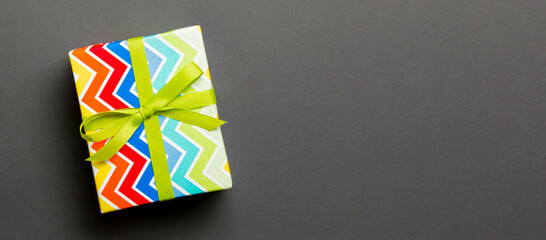 Top view Christmas present box with green bow on black background with copy space