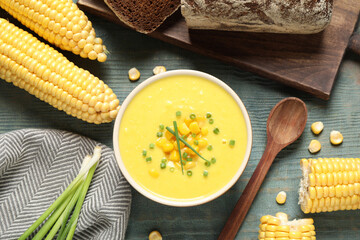 Delicious creamy corn soup served on blue wooden table, flat lay