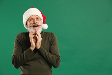 Happy bearded modern Santa Claus holds his hands together and rejoices on a green background