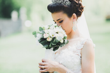 Beautiful luxury young bride in wedding dress posing in park