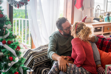 Adult couple caucasian people in love kissing and sharing sweetness at home during christmas winter...