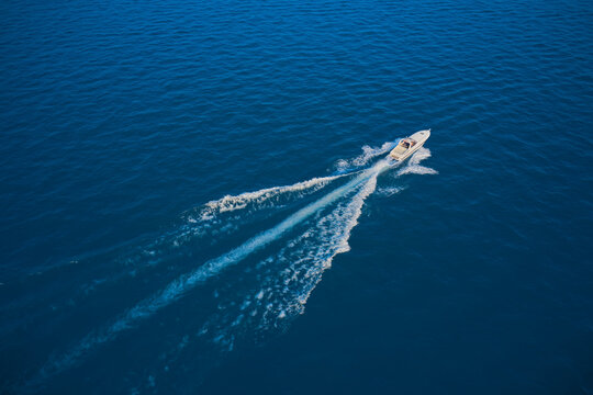 Yacht in the rays of the sun on blue water.  Aerial view luxury motor boat. Drone view of a boat sailing. Travel - image. Large speed boat moving at high speed side view.