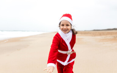 Obraz premium little girl in santa suit on the beach