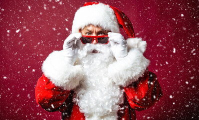 Close up portrait of a beautiful happy stylish Santa Claus is posing on a red background. Winter holidays and Merry Christmas