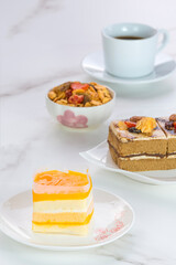 Orange soft cake, coffee cake and toppings with black coffee on marble tabletop in vertical frame, selective focus