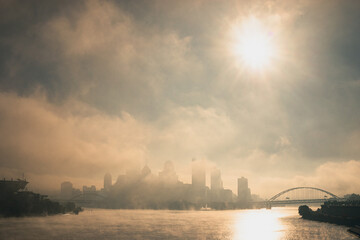 A foggy, misty morning over the Pittsburgh Ohio river with bridges and urban buildings and infrastructure.