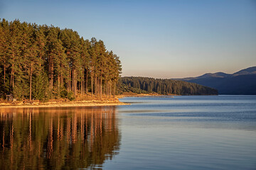 Fototapeta premium Idyllic mountain landscape at lake with calm water, tree reflection after sunset