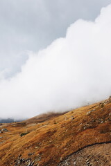 Cloudy day in mountains, clouds descend from the mountains to the village from above