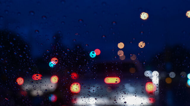 Rain drops on window with road light bokeh in night rainy