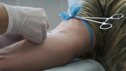 Fototapeta premium Close up footage nurse insert needle into man vein in order for the person to donate blood. Blood donation.