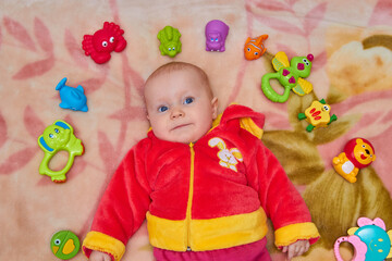 Fototapeta premium toys lie around the baby,baby lying in bed with toys shot from above