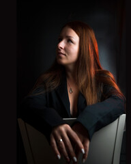 Portrait of a pretty girl with red hair, dressed in a black jacket. Portrait of a model in the Studio on a dark background.