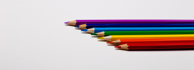 On a white background, color pencils close-up stacked according to the colors of the rainbow