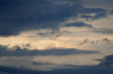 The evening sun shines easily through a dark cloud cover, orange sunshine, grey clouds in the sky