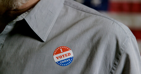 closeup of man putting a I voted sticker on his shirt