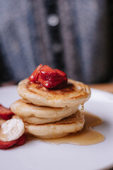 breakfast pancakes with mapple syrup and strawberries in a white plate