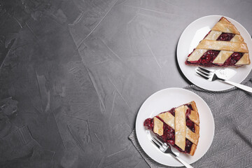 Slices of delicious fresh cherry pie served on grey table, flat lay. Space for text
