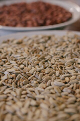 Roasted sunflower seeds in a plate in the foreground and peanuts in the background. Close-up.Macro shot. Selective focus.