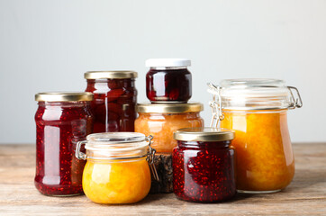 Fototapeta na wymiar Jars with different jams on wooden table