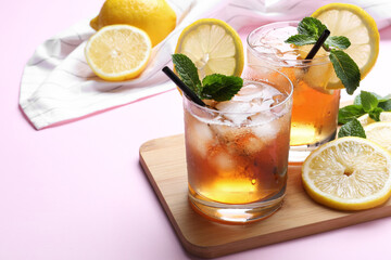 Delicious iced tea with lemon and mint on pink background, closeup