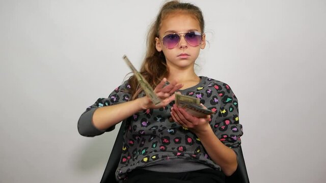 Imperturbable young girl sitting in a chair and throwing money. Big boss