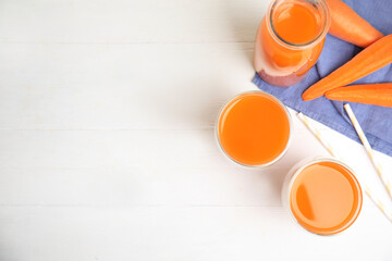 Freshly made carrot juice on white wooden table, flat lay. Space or text