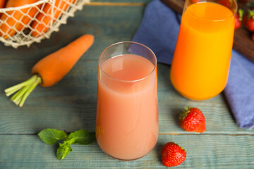 Glasses of delicious juices and fresh ingredients on blue wooden table