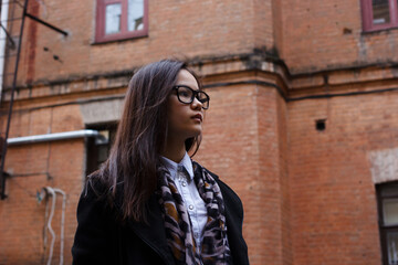 Fototapeta premium Portrait of beautiful Asian businesswoman standing outdoor on a building background with a brick wall