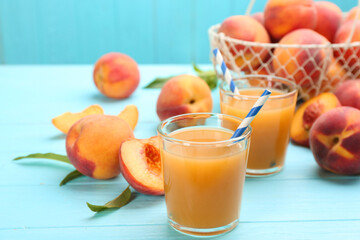 Natural peach juice and fresh fruits on light blue wooden table