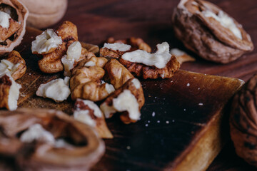 Walnut kernels and whole walnuts on rustic old wooden table.