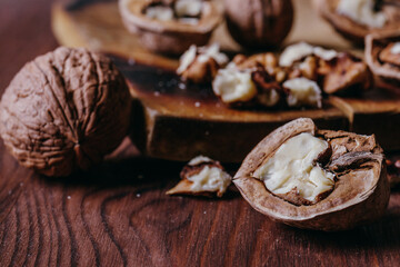 Walnut kernels and whole walnuts on rustic old wooden table.