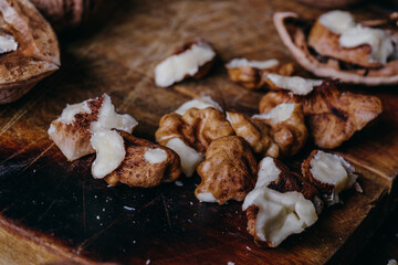 Cracked walnut kernels. Close-up on rustic old wooden table. Macro shot.