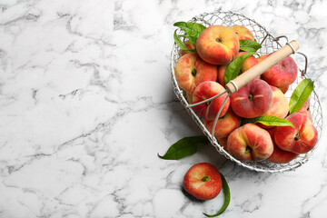 Fresh ripe donut peaches with leaves on white marble table, flat lay. Space for text