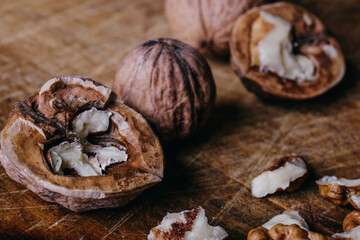 Walnut kernels and whole walnuts on rustic old wooden table.