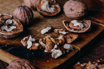 Walnut kernels and whole walnuts on rustic old wooden table.
