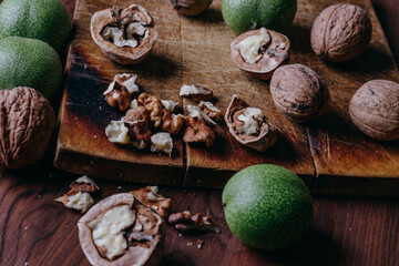 Walnut kernels, whole walnuts and green walnuts on rustic old wooden table.