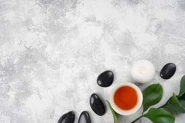 Obraz na płótnie Canvas Tea cups, black spa stones, candles, plant on light gray concrete background. Wellness concept. Top view, flat lay, copy space