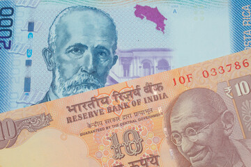 A macro image of a orange ten rupee bill from India paired up with a colorful two thousand colones bank note from Costa Rica.  Shot close up in macro.