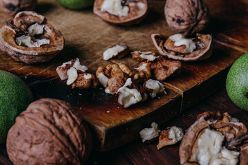 Walnut kernels, whole walnuts and green walnuts on rustic old wooden table.