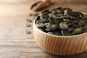 Peeled pumpkin seeds on wooden table, closeup