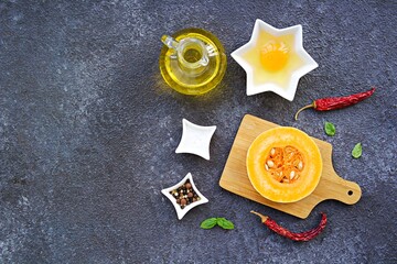 Prepared ingredients for cooking eggs in a pumpkin ring on a dark concrete background. Pumpkin recipes. Thanksgiving day concept. American cuisine. Top view.