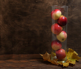 homemade juicy red apples in a transparent vase autumn fruits and vegetables on a brown wooden background fresh vitamins healthy food concept