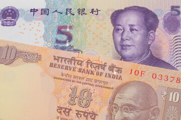 A macro image of a orange ten rupee bill from India paired up with a purple, blue and white five yuan bank note from China.  Shot close up in macro.