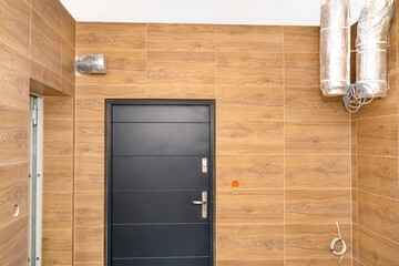 Modern gas boiler room with brown ceramic tiles imitating wood, visible air inlet and outlet, prepared for mounting the device used for home energy recovery ventilation.