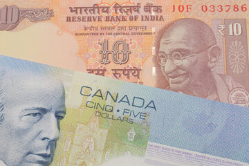 A macro image of a orange ten rupee bill from India paired up with a blue five dollar bill from Canada.  Shot close up in macro.