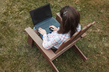 Young woman working remotely on a laptop in the garden