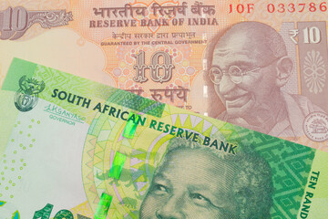 A macro image of a orange ten rupee bill from India paired up with a shiny, green 10 rand bill from South Africa.  Shot close up in macro.