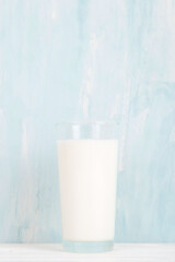 Milk in a glass glass on the table on a blue background. Copy space.